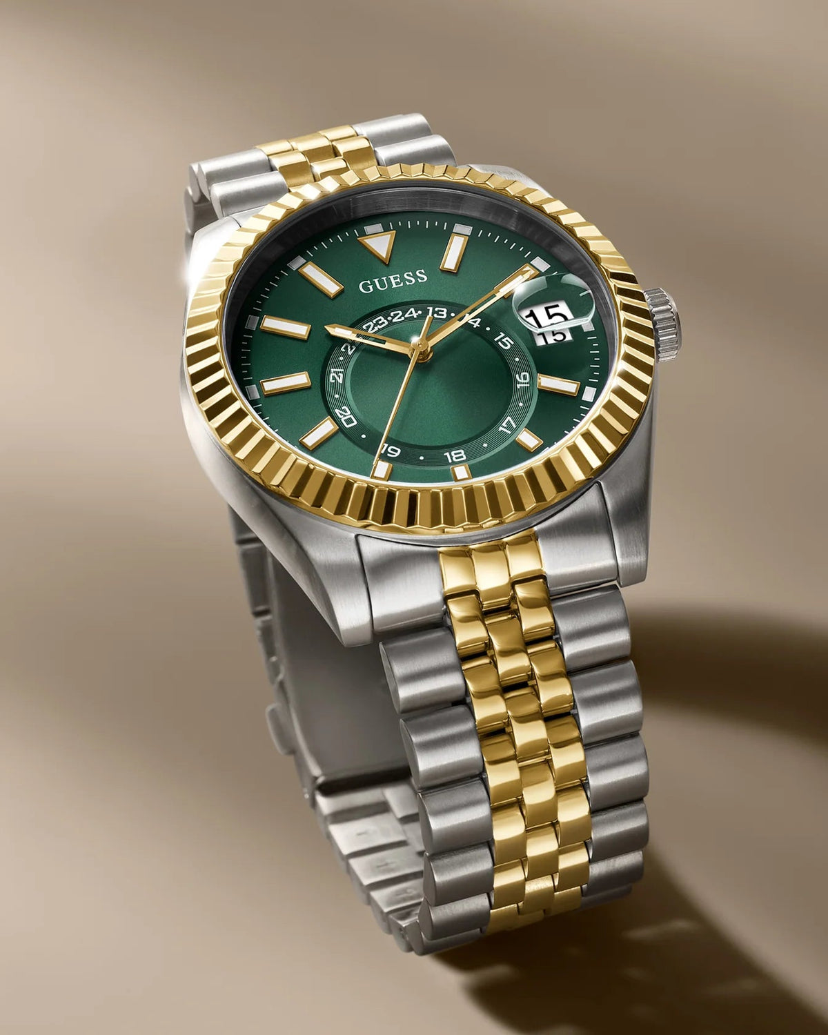 A two-tone Obey watch with a green dial, gold fluted bezel, and a silver-and-gold link bracelet, shown floating against a warm beige background.